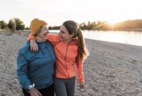 Zwei Frauen gehen an einem Flussufer spazieren und umarmen einander