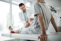 Arzt untersucht Knie bei Patient